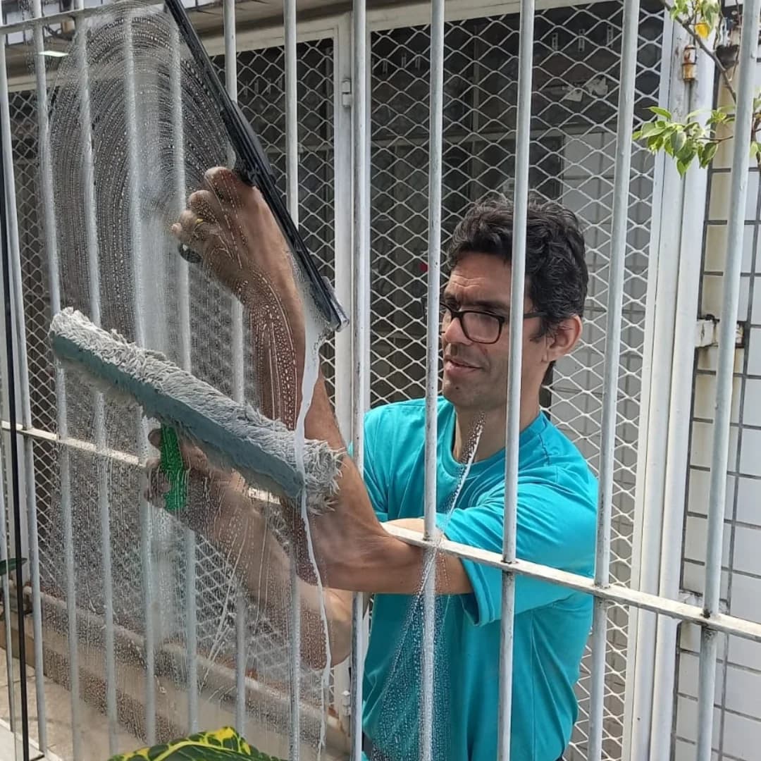 Profissional da ARM limpando um grande vidro em ambiente residencial