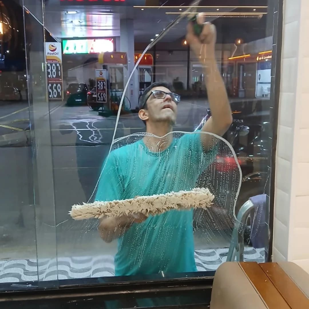 Profissional da ARM realizando limpeza de vidro em ambiente comercial